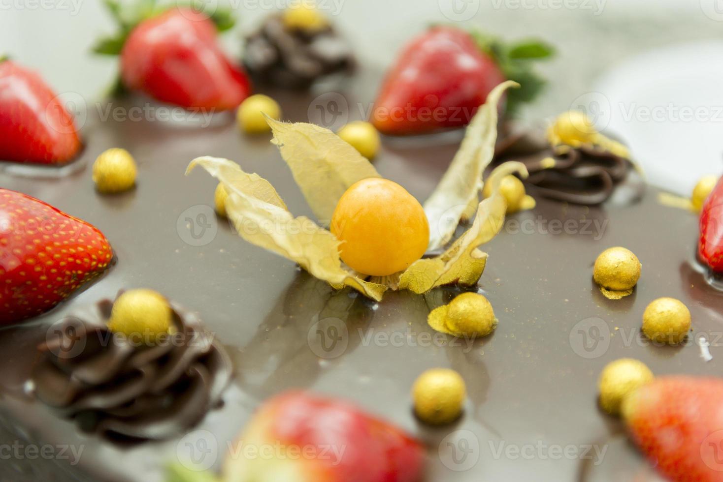 närbild av chokladkaka med physalis och jordgubbe. foto