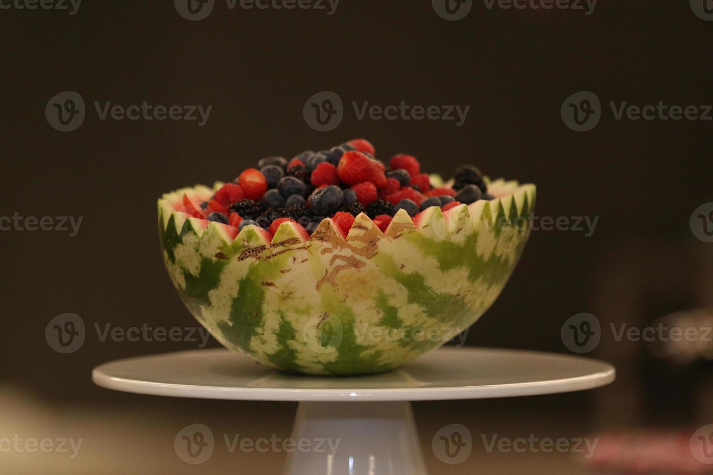 en halv vattenmelon fylld med olika frukter foto
