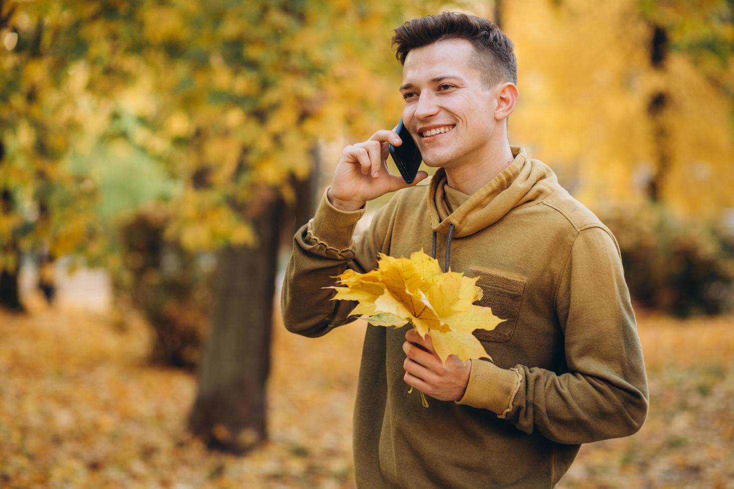 glad kille leende och prata i telefon i höstparken foto