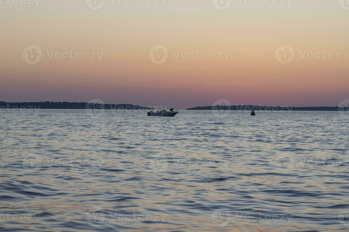 bild av de solnedgång tagen från de strand av de kroatisk kust stad av fazana med en motorbåt foto