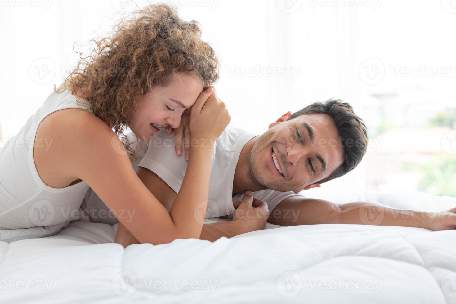 lyckliga par som kopplar av i det vita sovrummet i lägenheten foto
