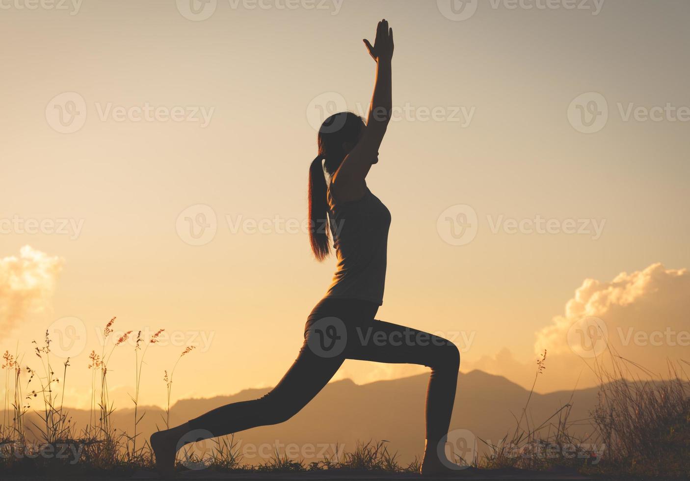 siluettkvinna som utövar yoga på toppen av berget foto