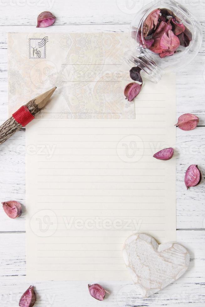 papper med penna, kronblad och hjärta foto