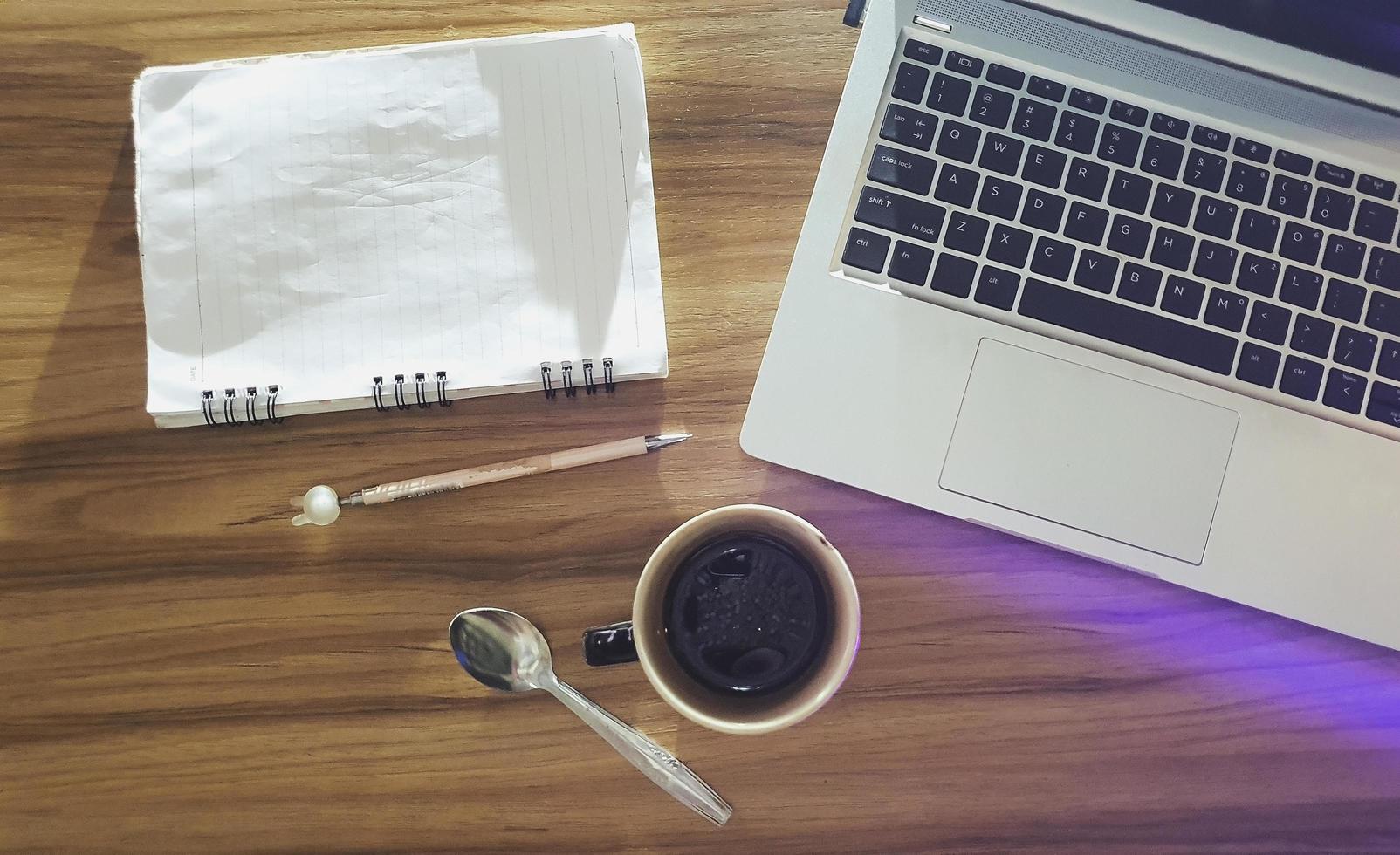 ovanifrån trä kontorsbord med laptop kopp kaffe och anteckningsbok foto