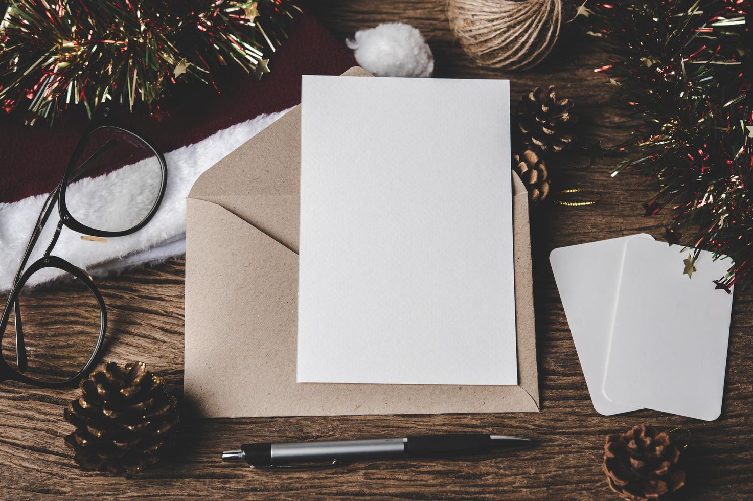 kuvert, blankt kort, glasögon och en penna läggs på trä. foto