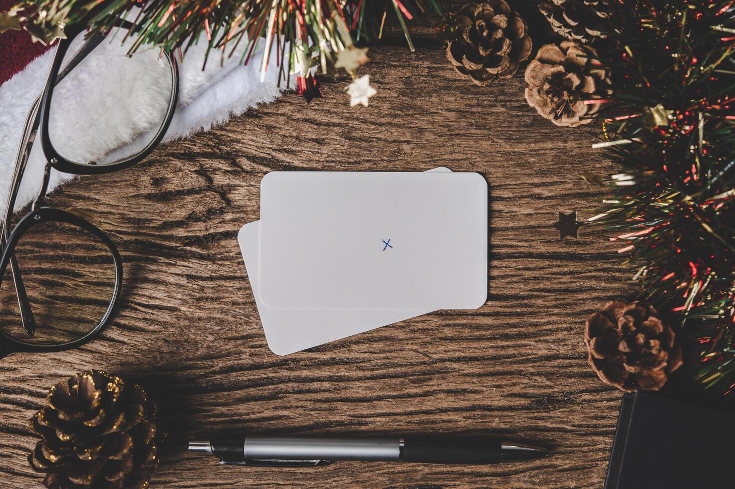 ett tomt kort, glasögon och en penna läggs på trä. foto