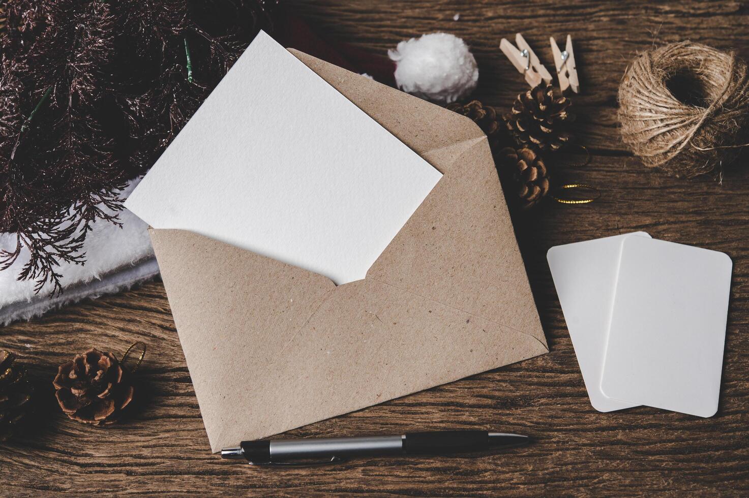 kuvert, blankt kort och en penna läggs på trä. foto