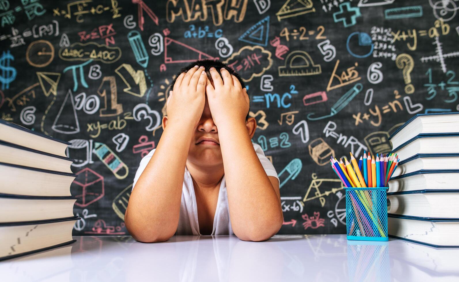 barn som sitter med händerna blundar i klassrummet foto