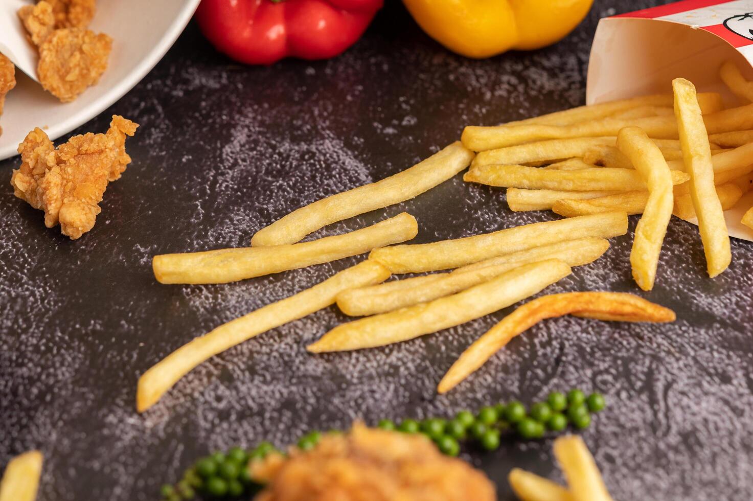 stekt kyckling och pommes frites på svart cementgolv. foto