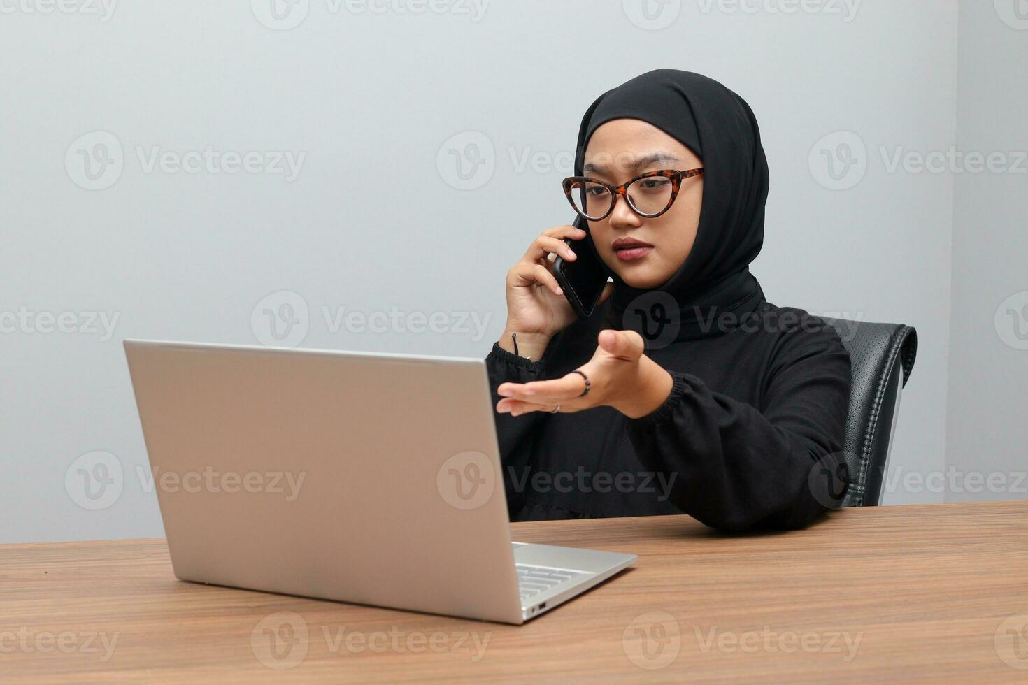 porträtt av attraktiv asiatisk hijab kvinna arbetssätt på henne bärbar dator. muslim flicka framställning en telefon ring upp i kontor. anställd och frilans arbetstagare begrepp. foto