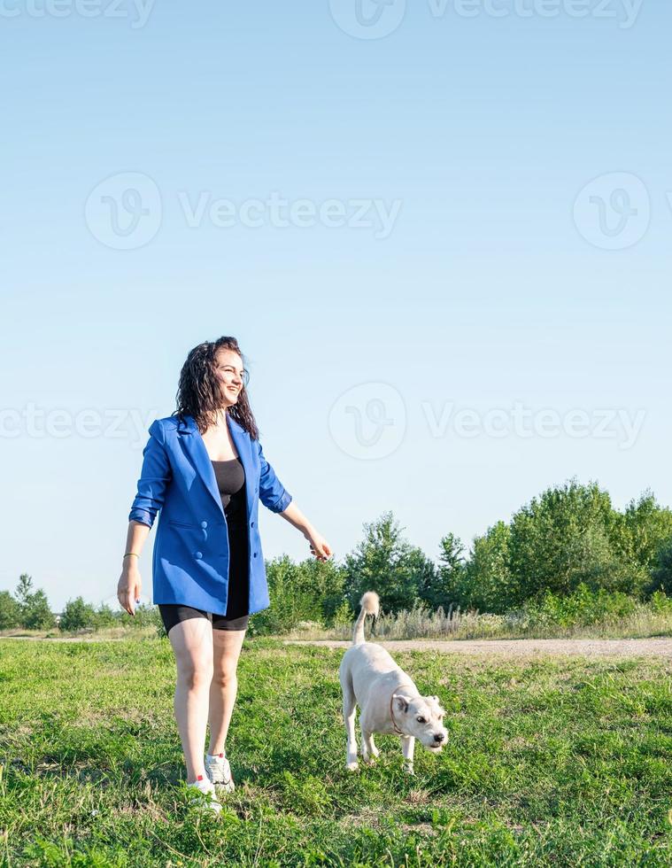 ung attraktiv kvinna som går sin hund i parken på sommardag foto