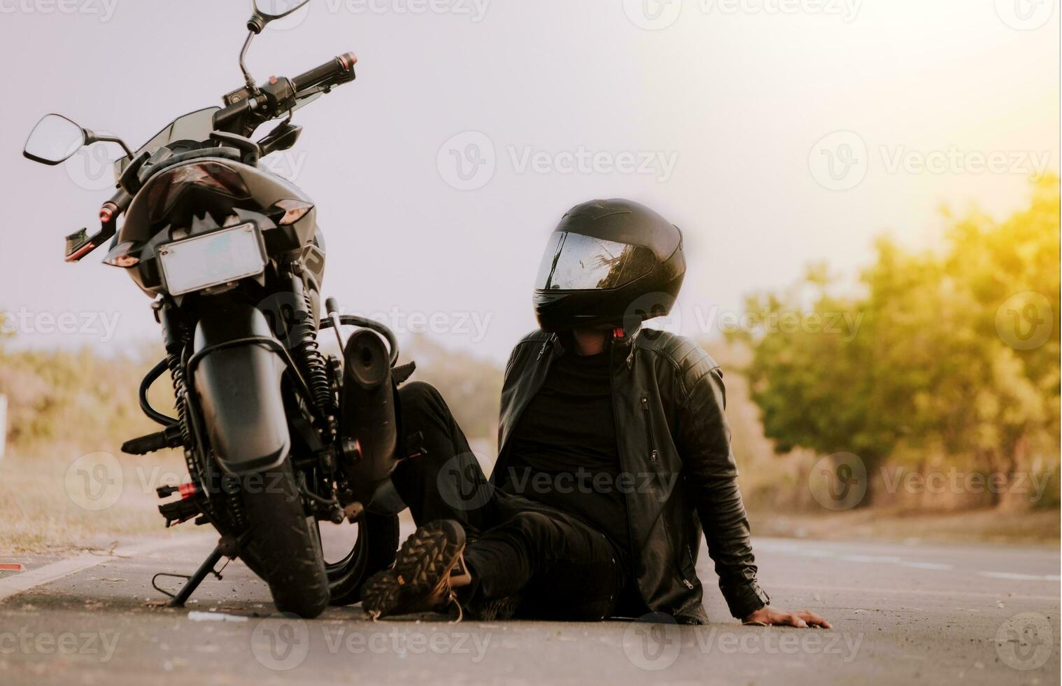 motorcyklist Sammanträde Nästa till hans motorcykel. motorcyklist Sammanträde och lutande på hans motorcykel på de asfalt foto