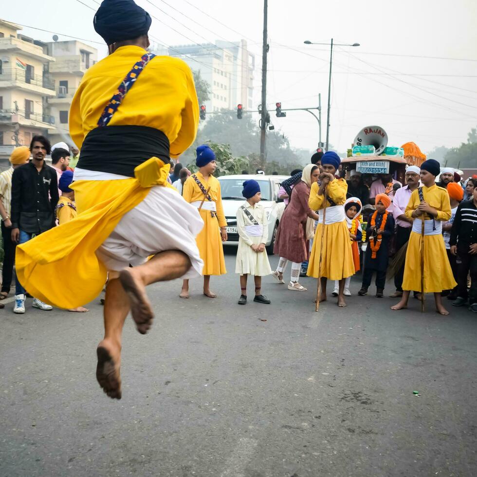 delhi, Indien, oktober 2, 2023 - sikher visa gatka och krigisk konst under årlig nagar kirtan, traditionell, procession på konto av födelsedag av guru nanak dev ji, nagar kirtan i öst delhi område foto