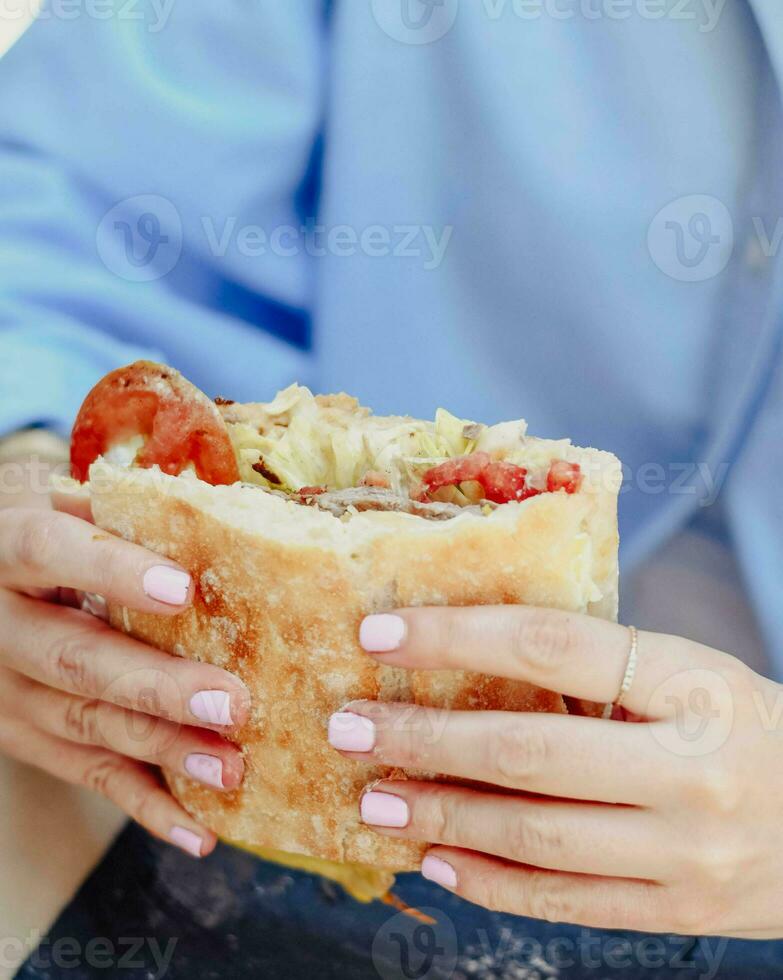 en ung person njuter en nötkött smörgås foto