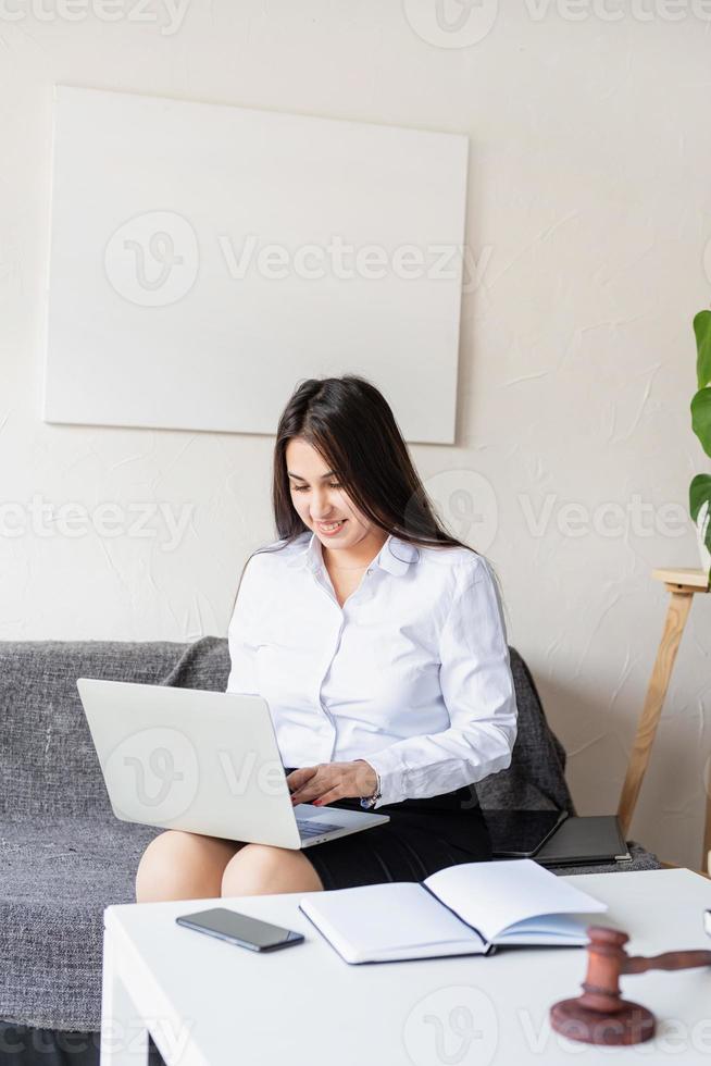 advokat som arbetar på den bärbara datorn sitter i soffan foto
