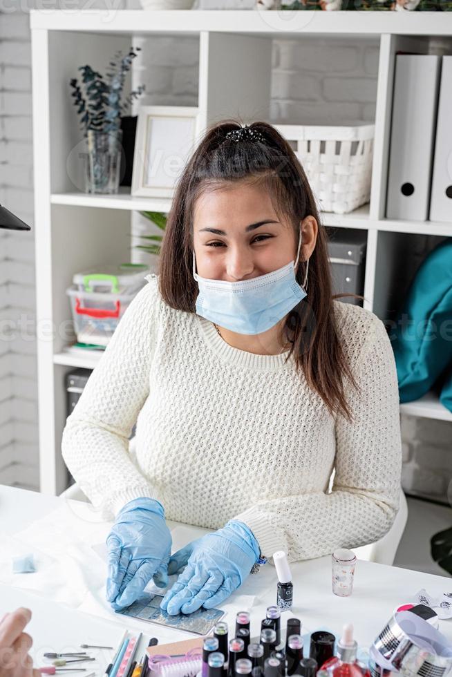 manikyrmästare i mask och handskar gör stämpling till klienten foto