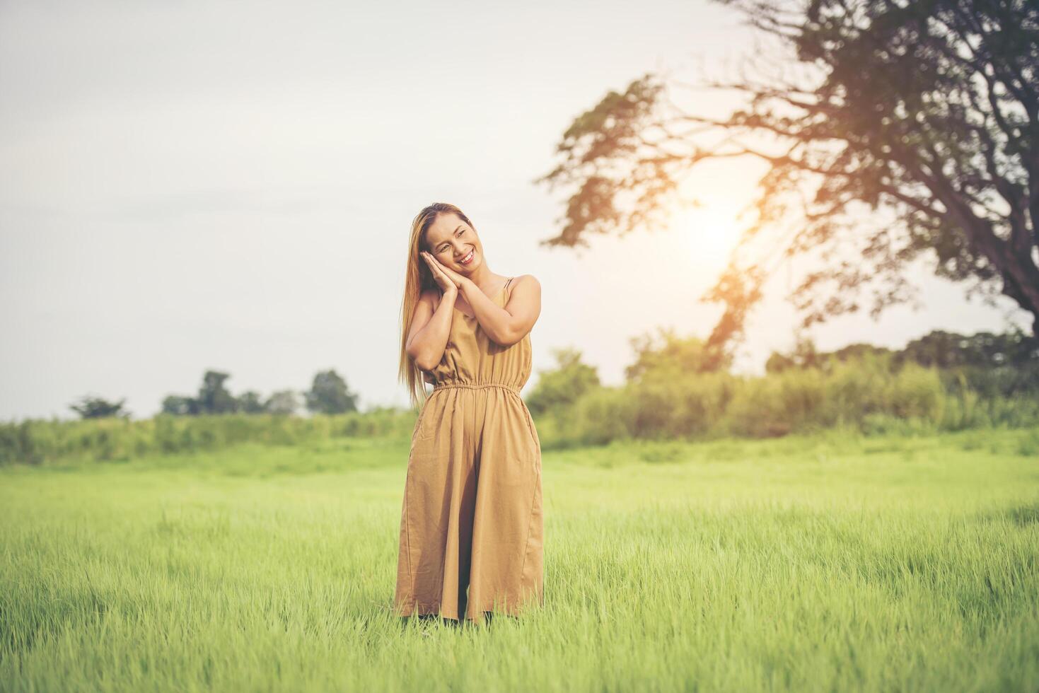 ung kvinna som står i gräsfältet som höjer händerna i luften. foto