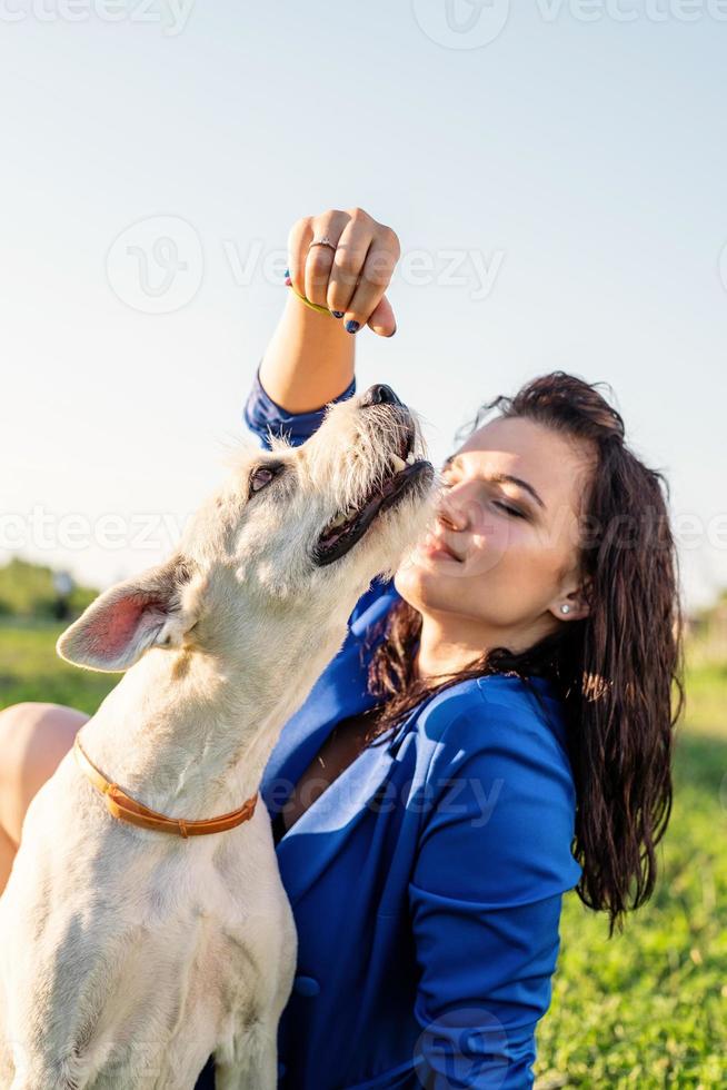 ung attraktiv kvinna som matar sin hund i parken foto