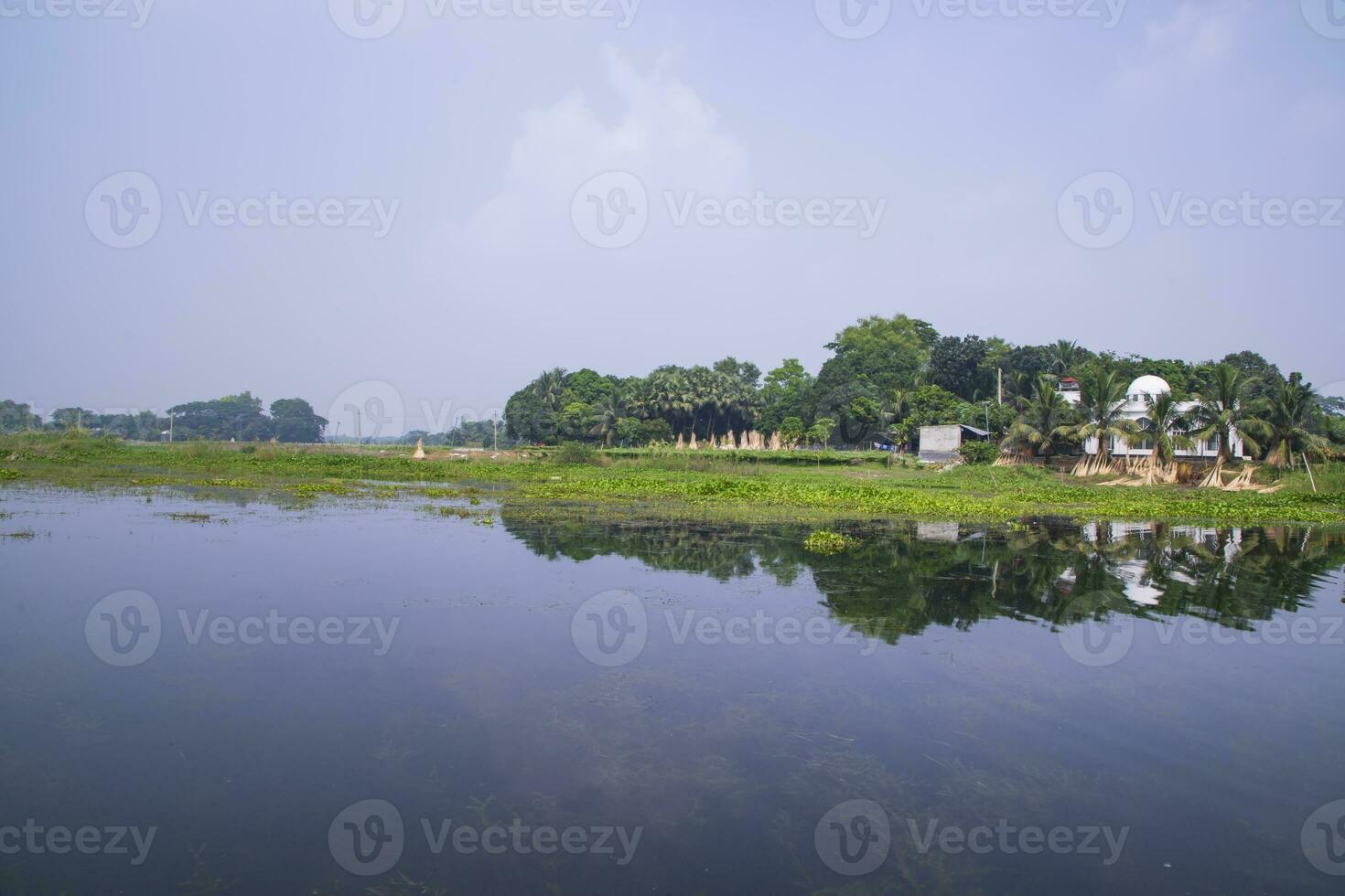 reflexion av träd i de sjö vatten mot de blå himmel landskap landsbygden i bangladesh foto