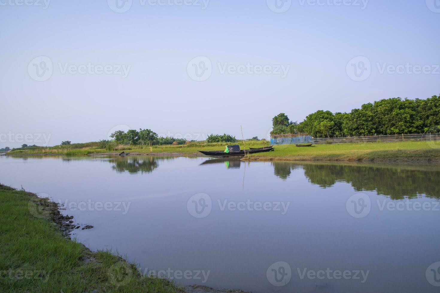 kanal med grön gräs och vegetation reflekterad i de vatten nära padma flod i bangladesh foto