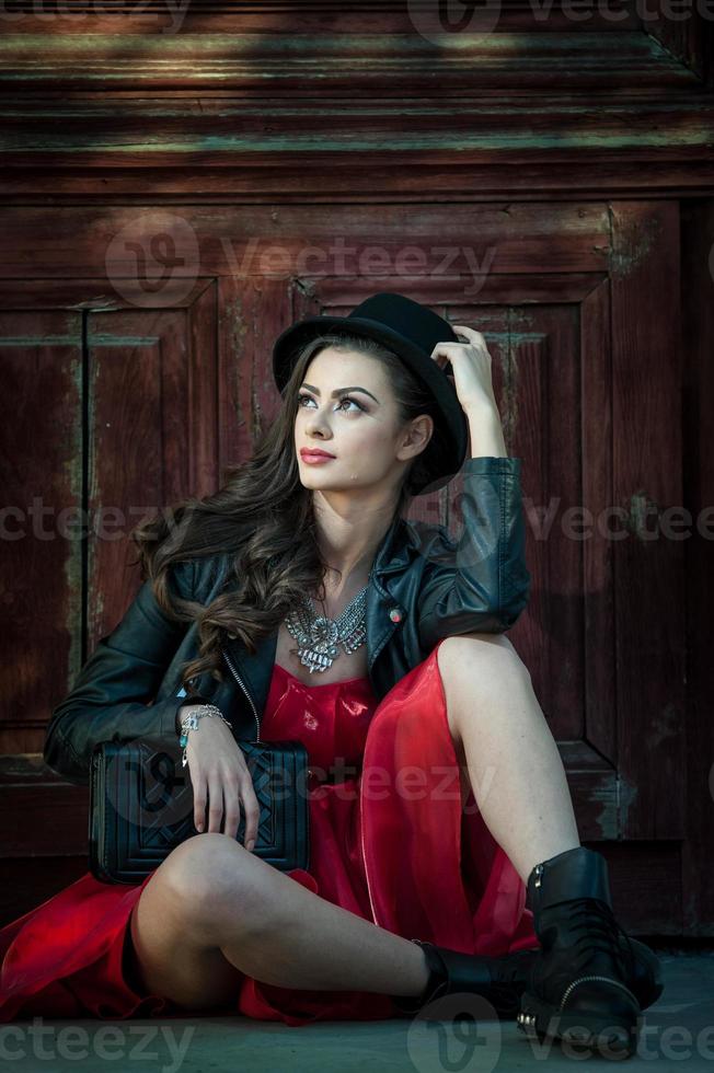 ung vacker brunettkvinna med röd kort klänning och svart hatt foto