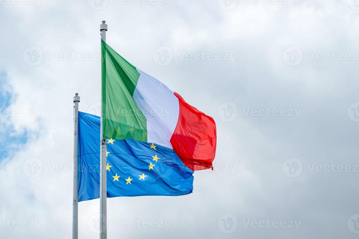 italienska och Europeiska unionens flaggor som vinkar mot en grumlig himmel foto