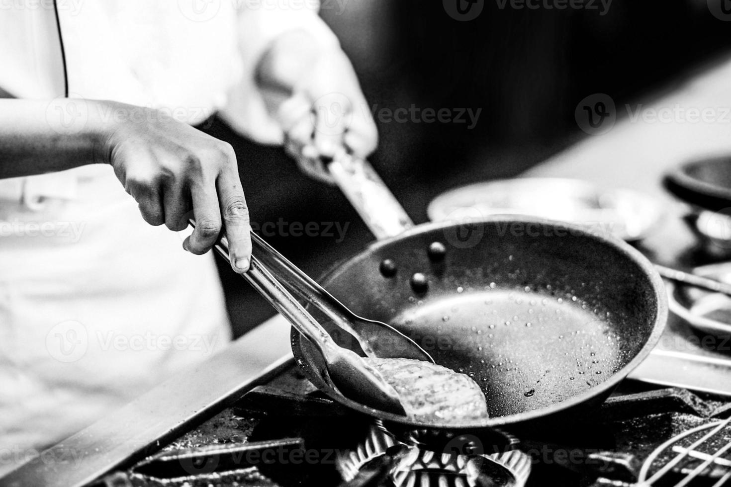 kock som lagar mat i ett kök, kock på jobbet, svartvitt foto