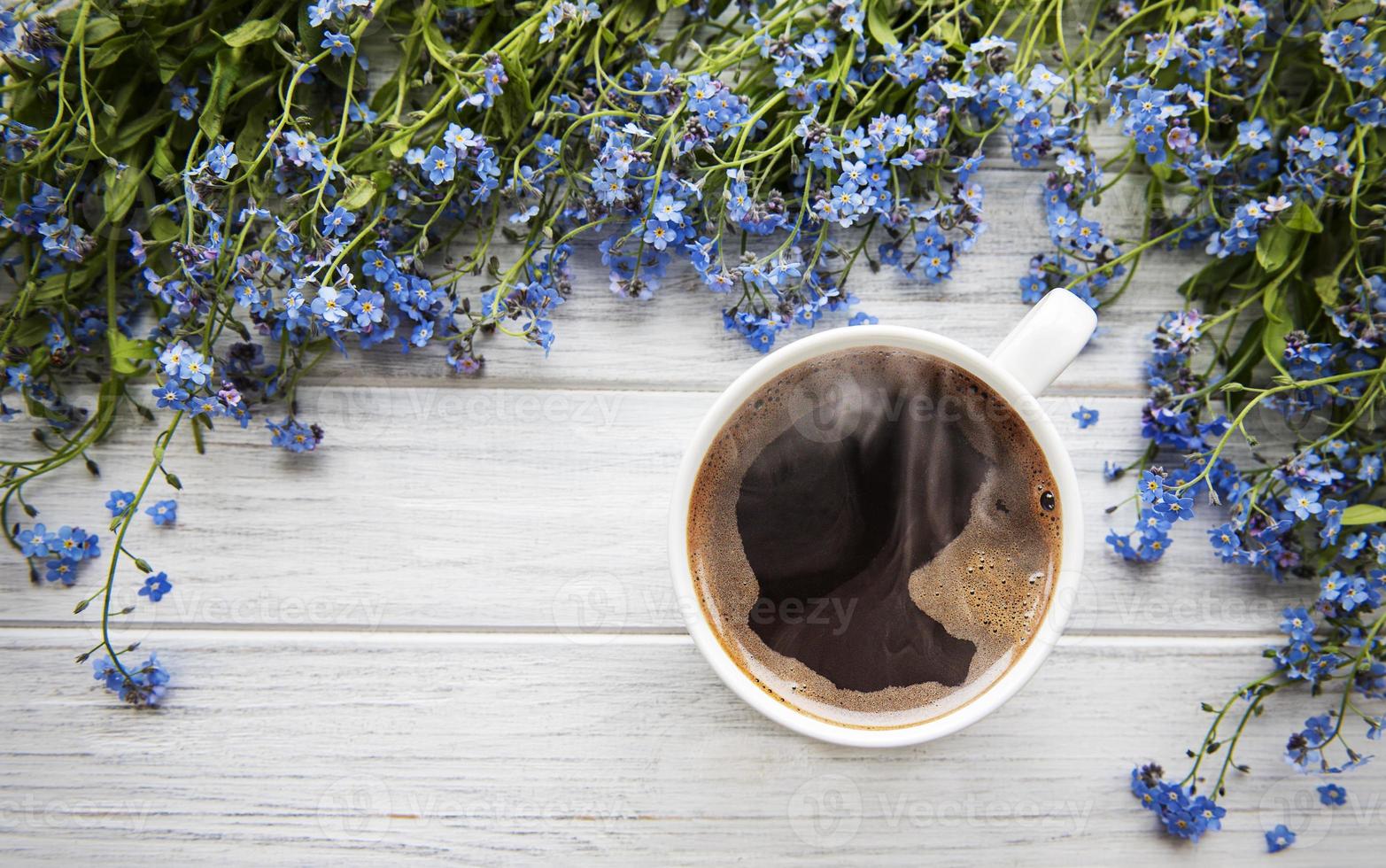 glöm-mig-inte blommor och kopp kaffe på en träbakgrund foto