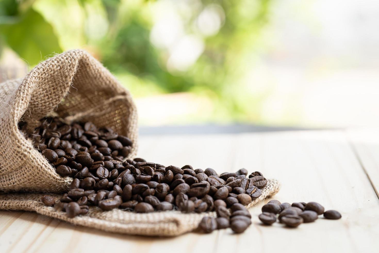 kaffebönor häller ut ur säcken på trägolvet på morgonen. foto