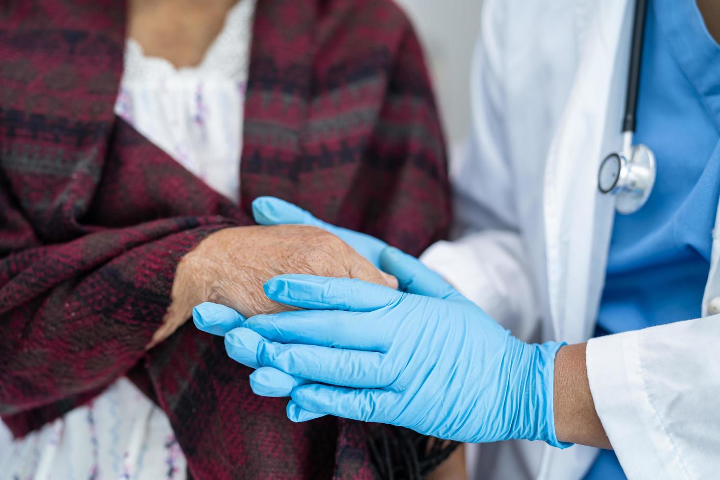 läkare som håller rörande händer asiatisk senior kvinna patient med kärlek foto
