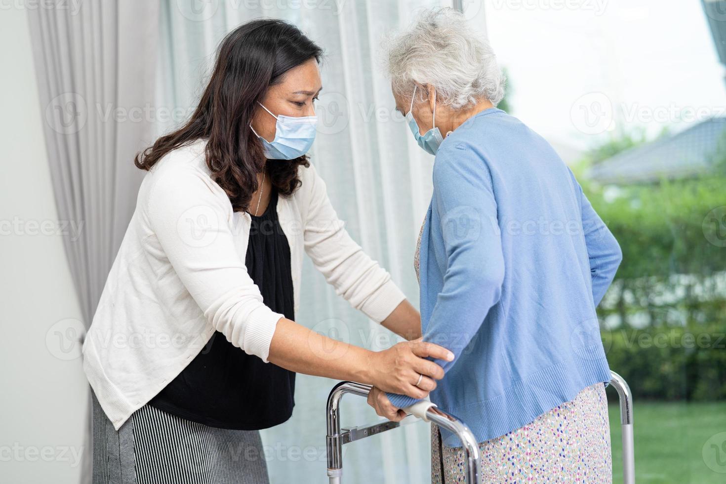 hjälp asiatisk senior kvinna patient gå med rullator på sjukhus. foto