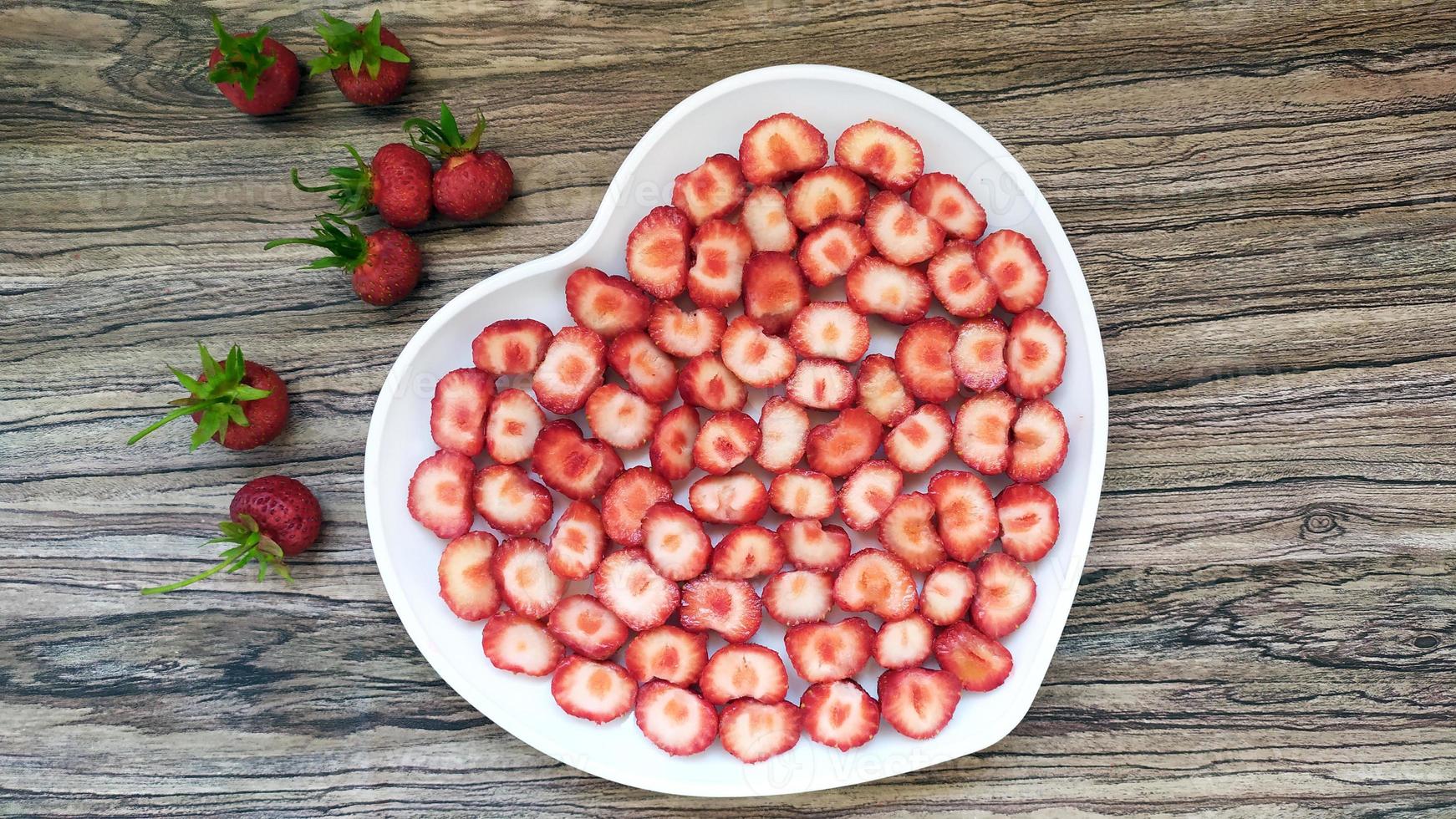 jordgubbar i en vit tallrik med ett hjärta. en romantisk servering foto