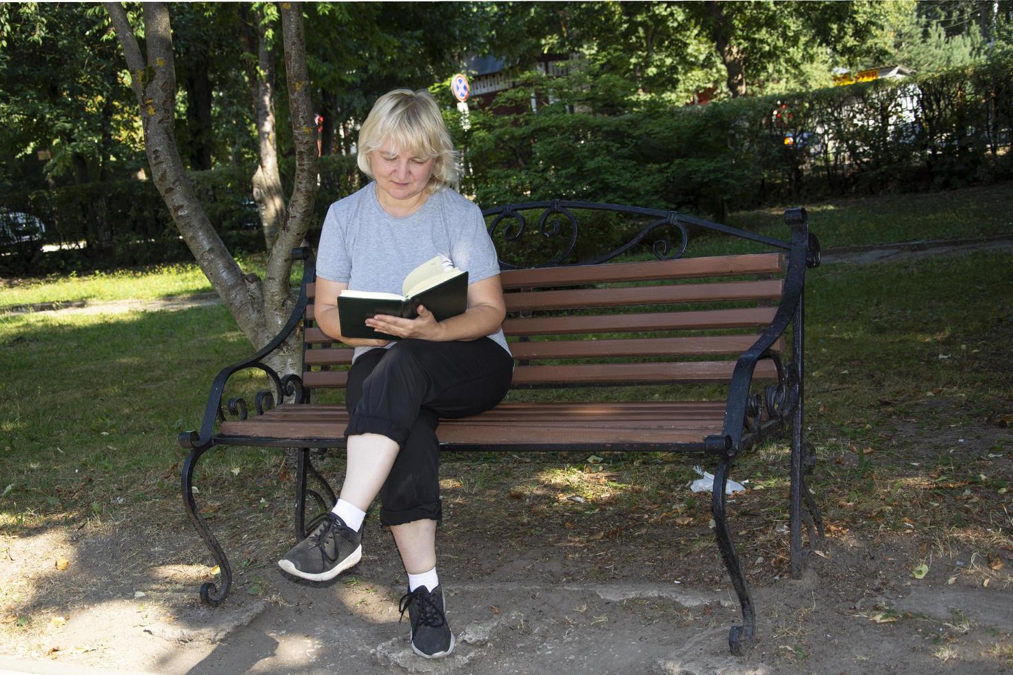 kvinnan läser en bok. människor vilar i en stadspark foto