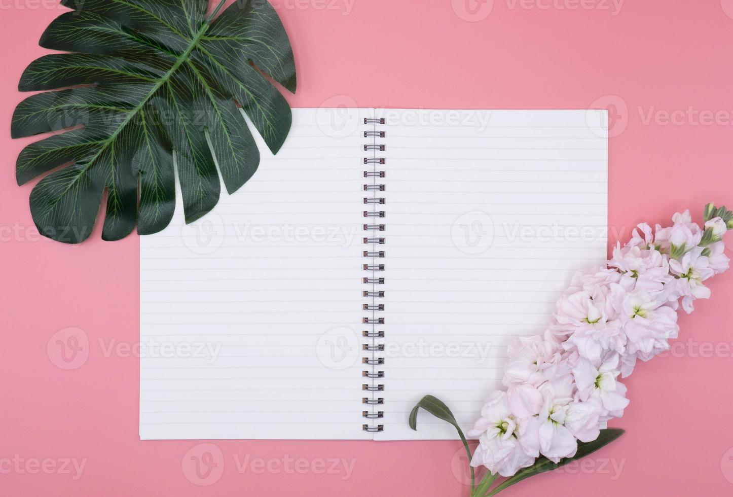 vit dagbok med blommor och gröna blad på rosa bakgrund foto