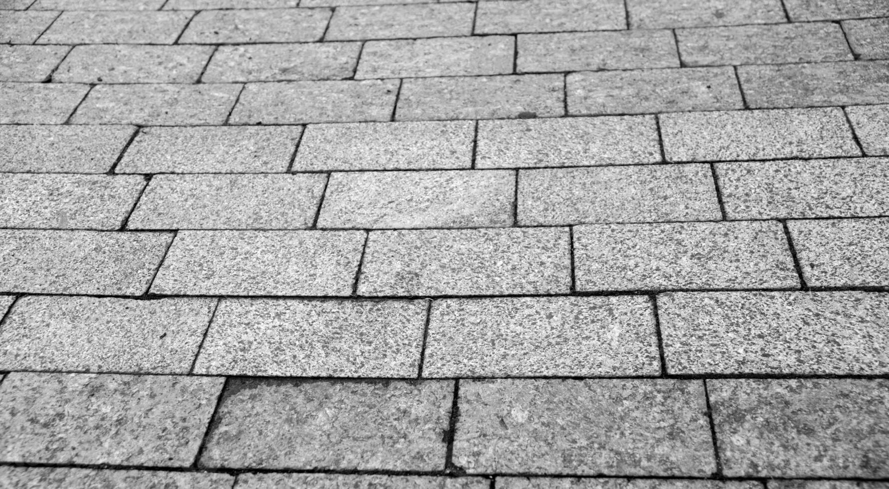 stad väg trottoar tillverkad av tegelstenar och stenar, väg textur i detalj svart och vit bakgrund foto