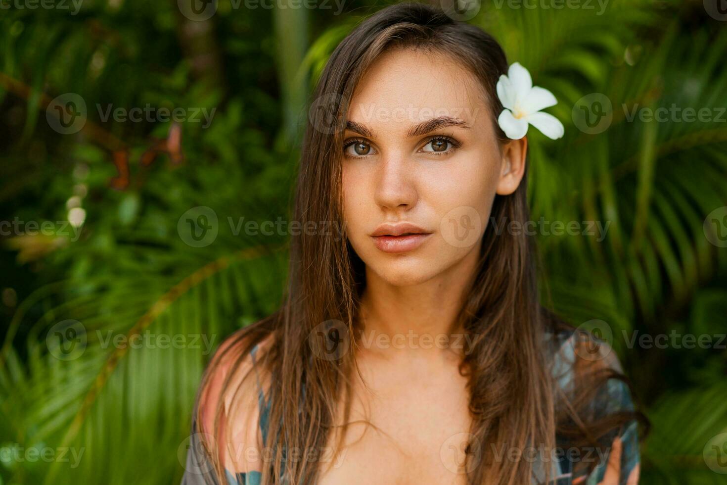 stänga graciös kvinna modell med plumeria blomma i hårstrån Framställ i tropisk natur. foto