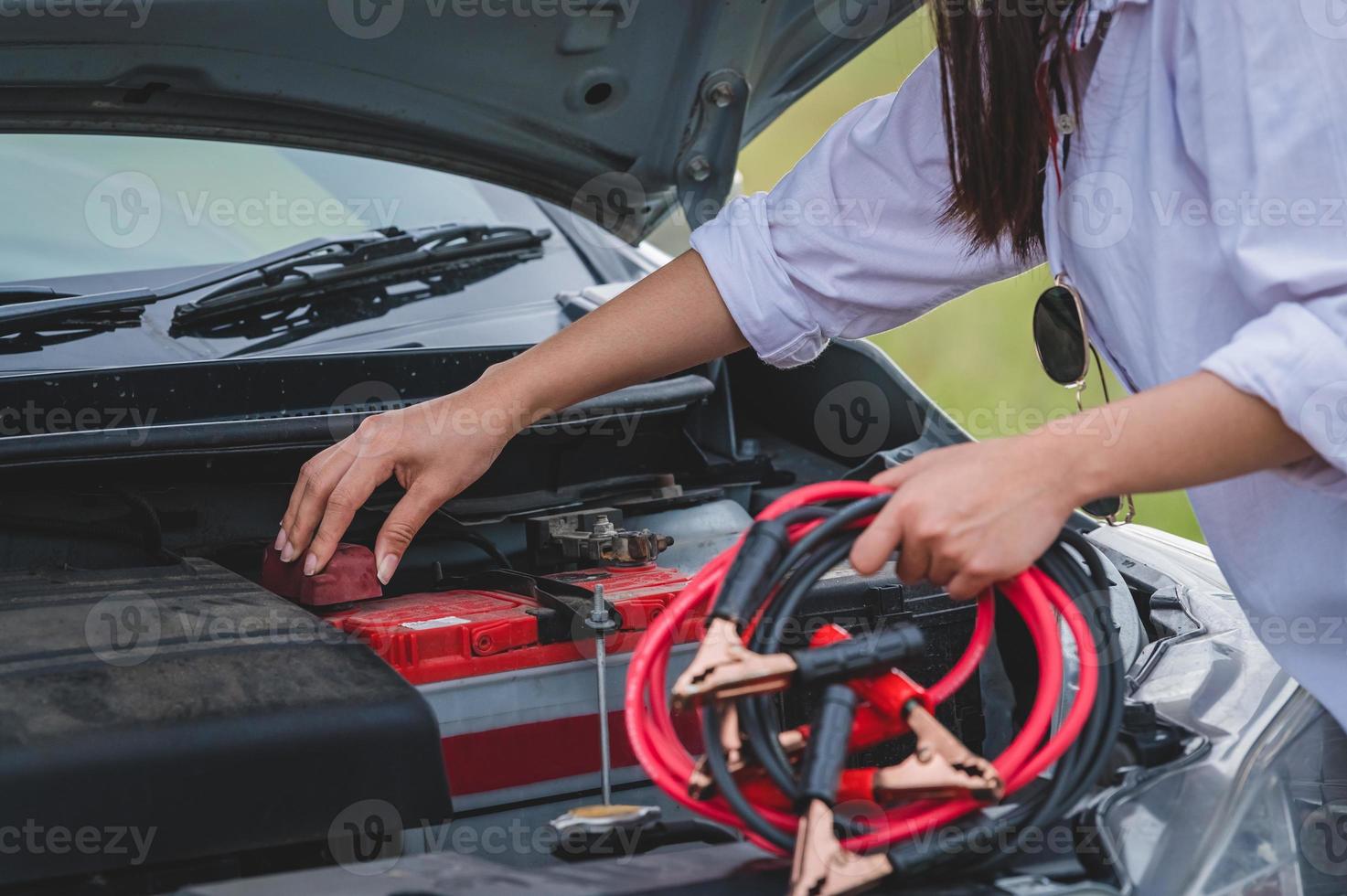 närbild av kvinnans hand som håller batterikabeln för reparation av bil foto