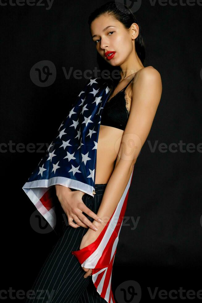 porträtt kvinna idrottare insvept i amerikan flagga mot svart bakgrund foto