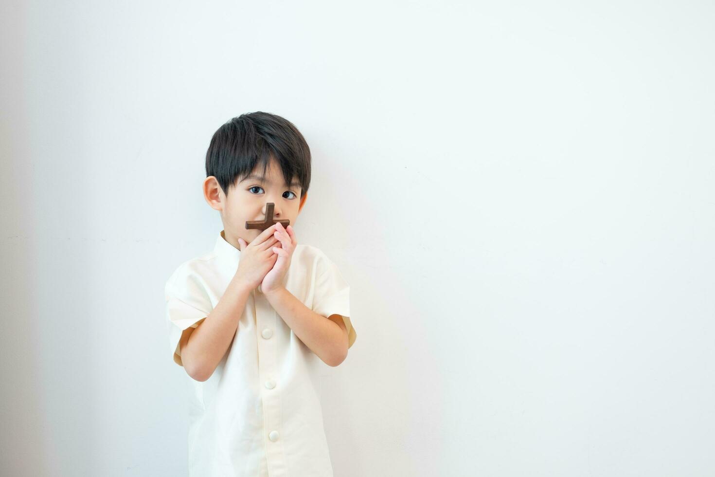 liten asiatisk pojke bön- med innehav de korsa, kristen begrepp foto