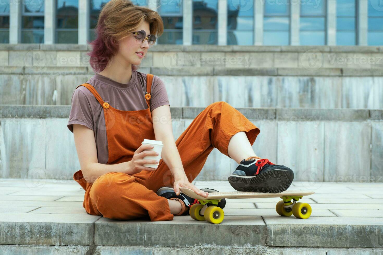 kvinna skater Sammanträde på steg med skateboard och kaffe behållare i henne hand. foto