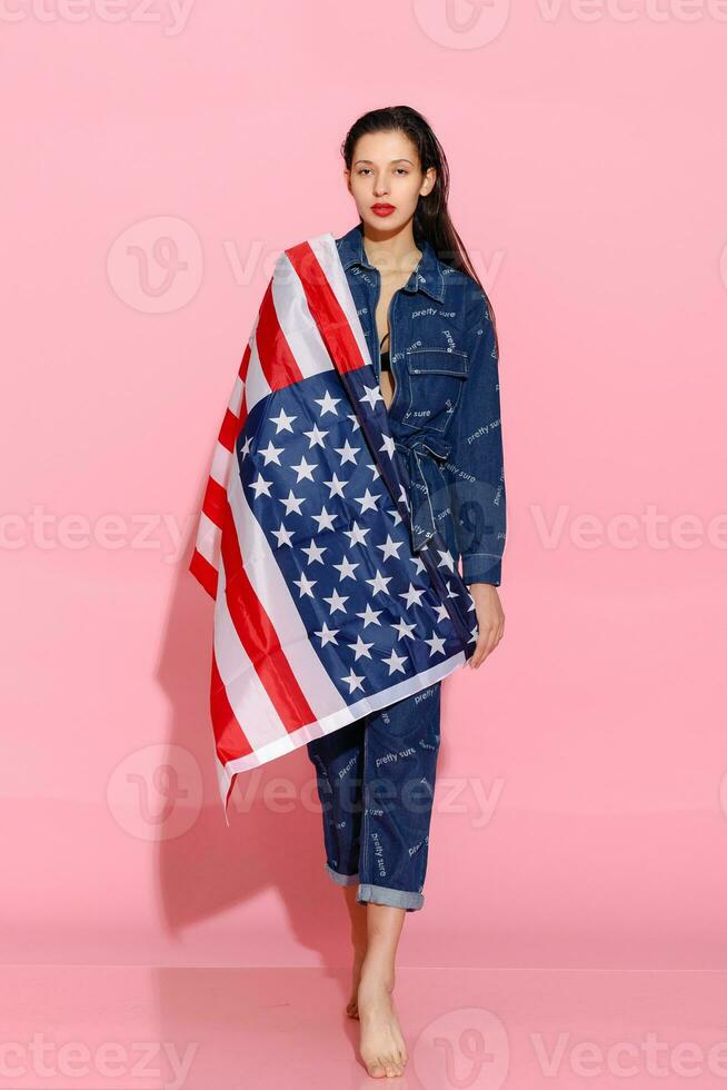 porträtt kvinna idrottare insvept i amerikan flagga mot rosa bakgrund foto
