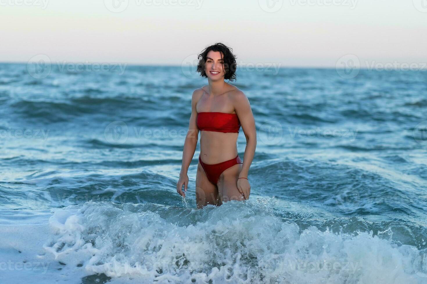 sexig tillbaka av en skön kvinna i röd bikini på hav bakgrund foto