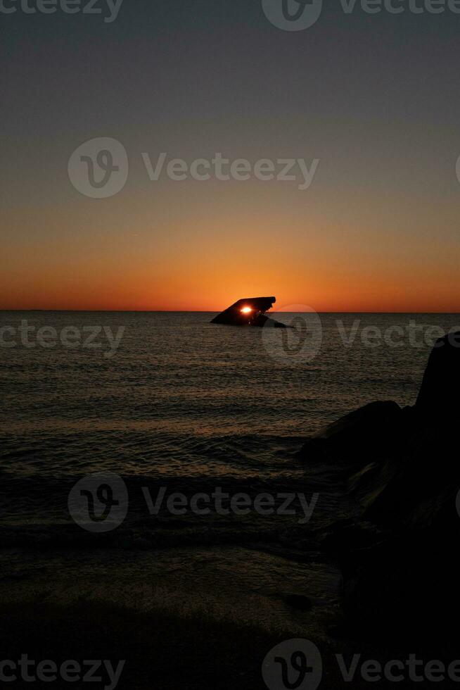 de nedsänkt fartyg av cape Maj ny jersey under solnedgång. de Sol foder upp perfekt med skrov till se tycka om en lysande öga. de himmel har skön färger av orange nästan tycka om den är på brand. foto