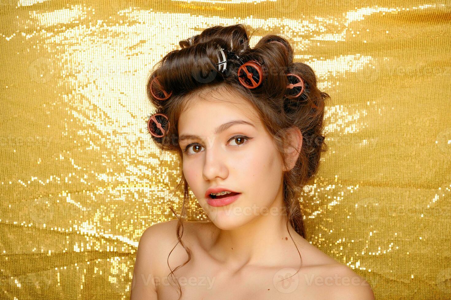skön flicka i hår papiljotter isolerat på guld foto