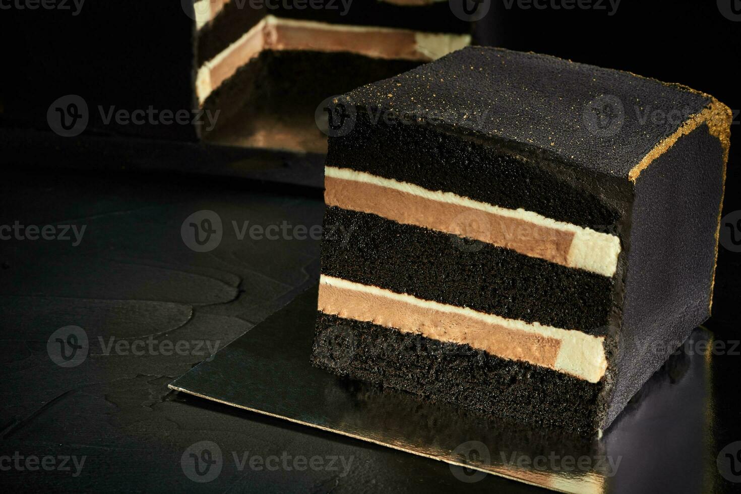 svart fyrkant kaka med guld kanter. mörk bakgrund. de se från de topp. foto