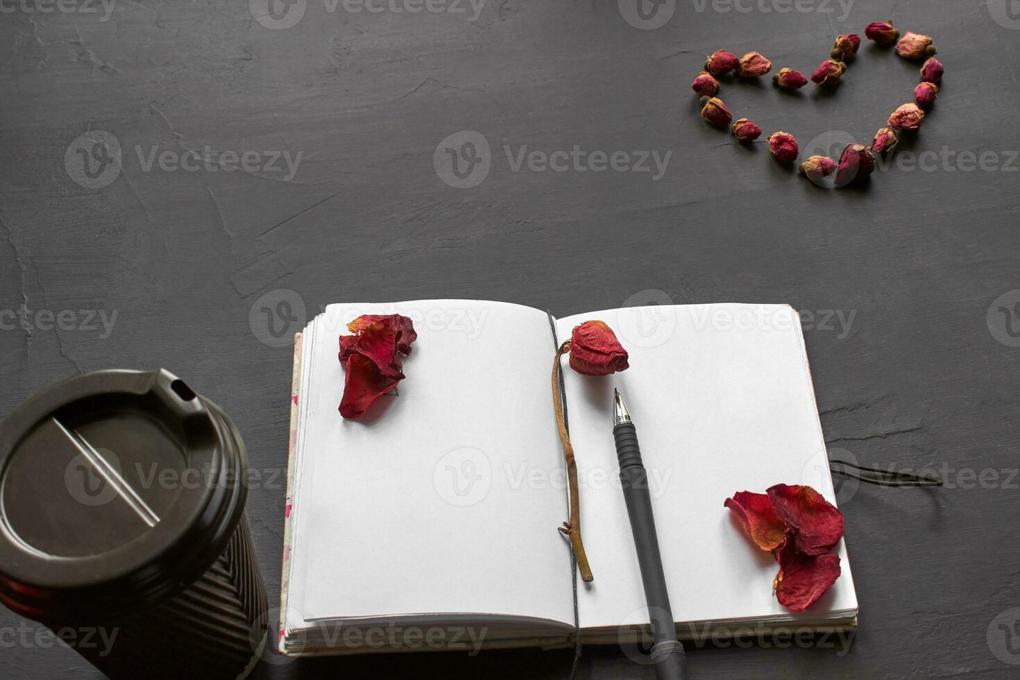 topp se av ett tömma anteckningsbok, klippbok Tillbehör och en kopp av kaffe på en svart bakgrund. foto