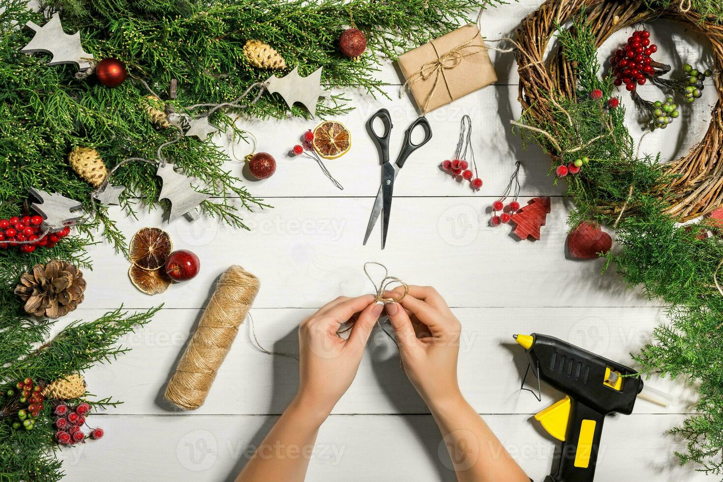 jul handgjort diy bakgrund. framställning hantverk xmas krans och ornament. topp se av vit trä- tabell med kvinna händer. foto