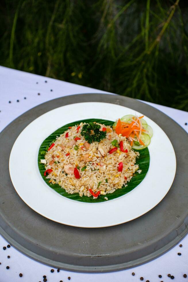 friterad ris med grönsaker, kyckling och chili sås är eras på en vit tallrik på de tabell foto