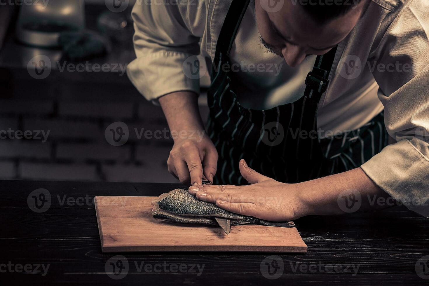 kock skärande de fisk på en styrelse foto