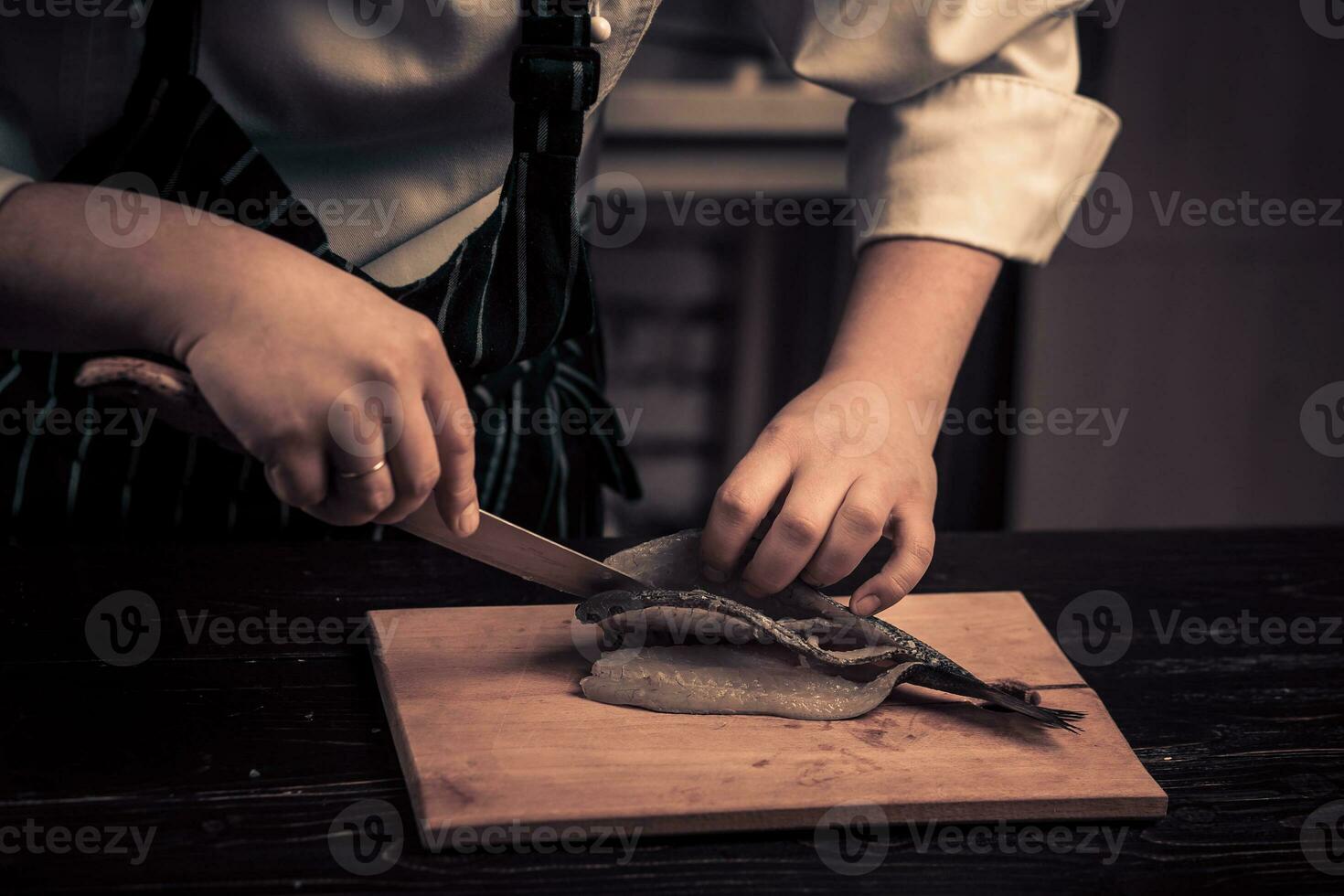 kock skärande de fisk på en styrelse foto